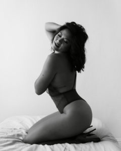 Black and white photo of a woman in a sultry boudoir pose